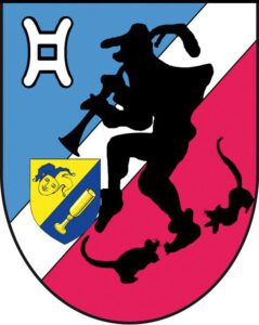 Wappen der Schlaraffia Reyche ob-der-hamel (336): Diagonale Teilung in Blau, Weiß und Rot mit der schwarzen Silhouette des Rattenfängers von Hameln, links oben ein weißes Mühleisen-Symbol und links unten ein kleines gelb-blaues Wappen mit Narrenkopf und Humpen. Ausführliche Beschreibung (für Barrierefreiheit-Unterseiten oder Bildunterschriften): Das Wappen ist schräglinks geteilt in den Farben Blau (oben links), Weiß (Mittelbalken) und Rot (unten rechts). Zentrales Motiv: Eine markante schwarze Silhouette des Rattenfängers von Hameln in dynamischer Pose, der eine Flöte spielt. Ihm folgen am rechten unteren Rand zwei schwarze Ratten. Obere linke Ecke: Ein weißes, stilisiertes Symbol, das einem Mühleisen oder einer heraldischen Spange ähnelt, auf blauem Grund. Mittlerer linker Bereich: Ein kleinerer, eingeblendeter Wappenschild, der schräg geteilt ist. Das obere goldene Feld zeigt das Gesicht eines Schlaraffen/Narren mit typischer Kappe; das untere blaue Feld zeigt einen goldenen Humpen (Stauf).